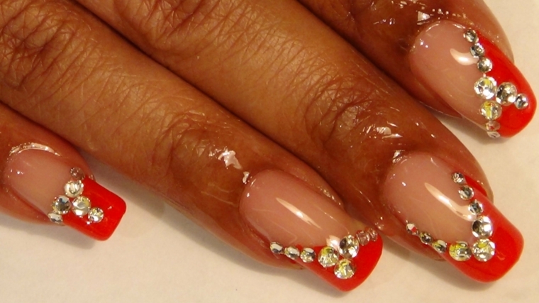 french manicure originale realizzata con dello smalto rosso e dei glitter di varie dimensioni 